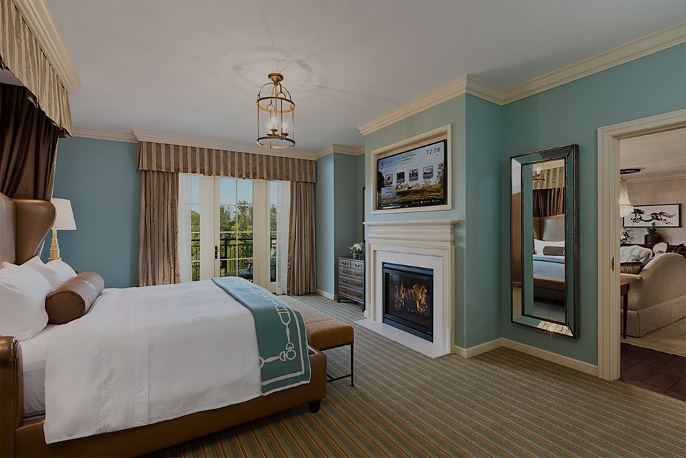 Elegant blue bedroom with French doors, fireplace, and TV
