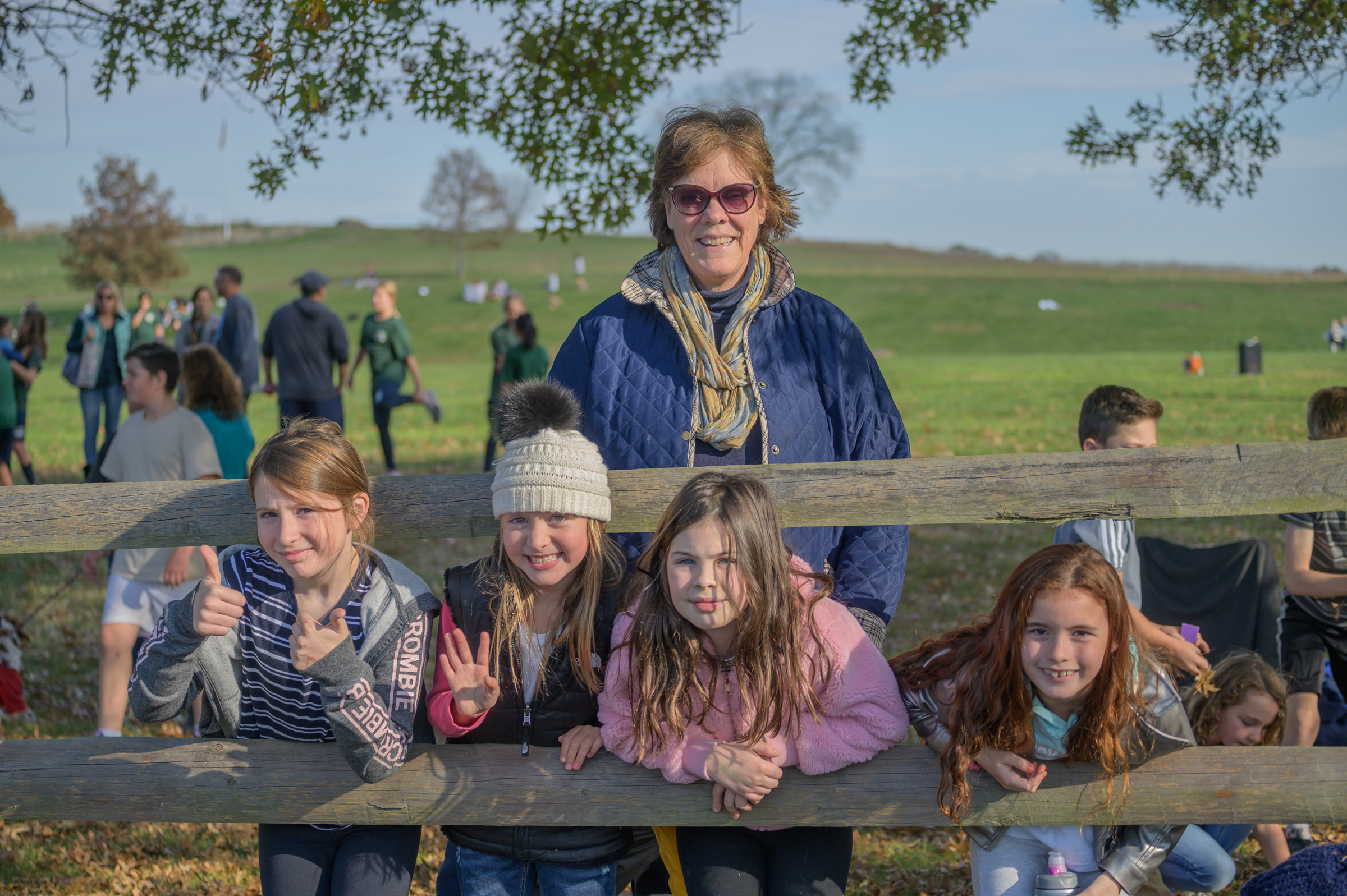 kids waving leaning through post and rail fence with coach