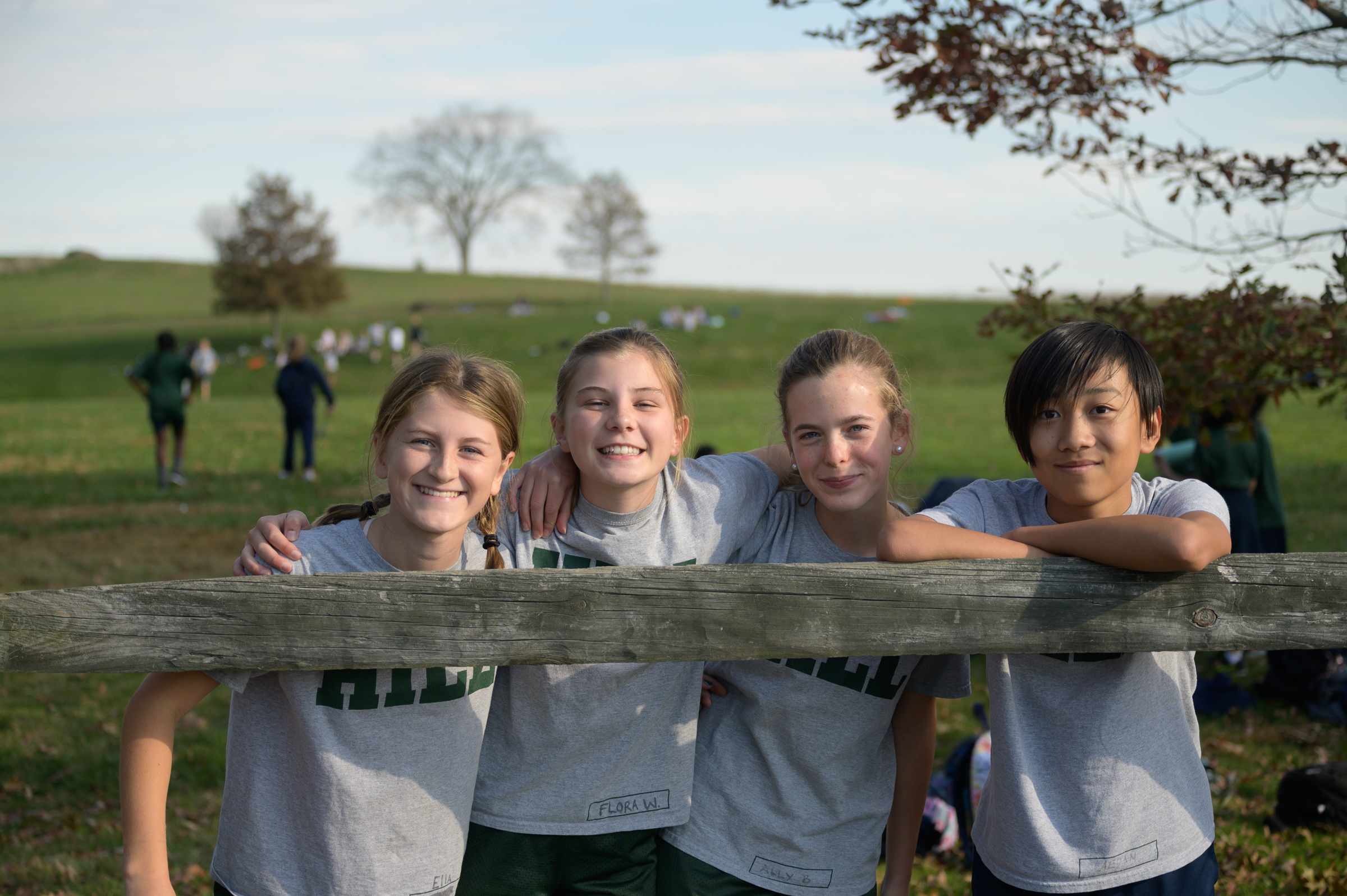 kids similing leaning on post and rail fence