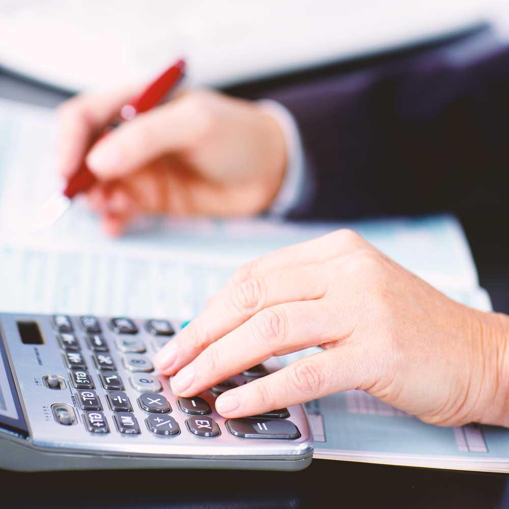 hands at desk with pen and calculator