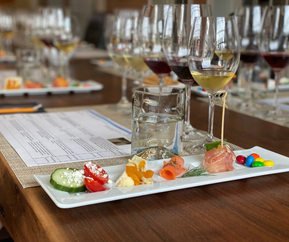 Small tray of appetizers next to water glass and a sampling of wines in glasses