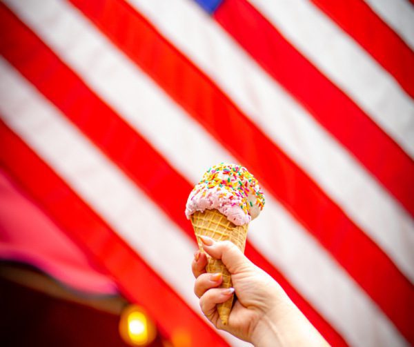hand holding ice cream cone in front of American Flag